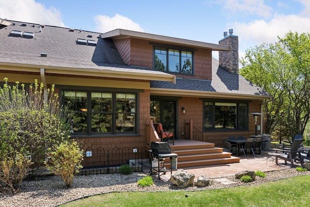 rear view of property with a patio, a shingled roof, and a chimney