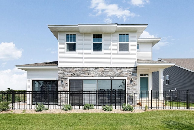 view of front of home with a front lawn, fence, and stone siding