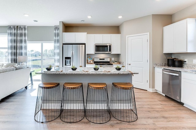 kitchen featuring stainless steel appliances, a breakfast bar, and white cabinetry
