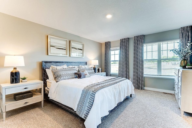 bedroom featuring baseboards, a textured ceiling, and light colored carpet