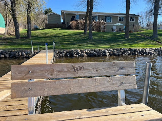 view of dock featuring a lawn and a water view