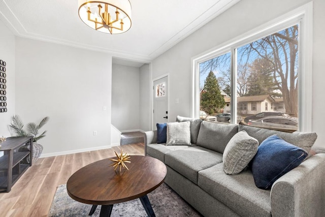 living area with an inviting chandelier, baseboards, a wealth of natural light, and light wood-style floors