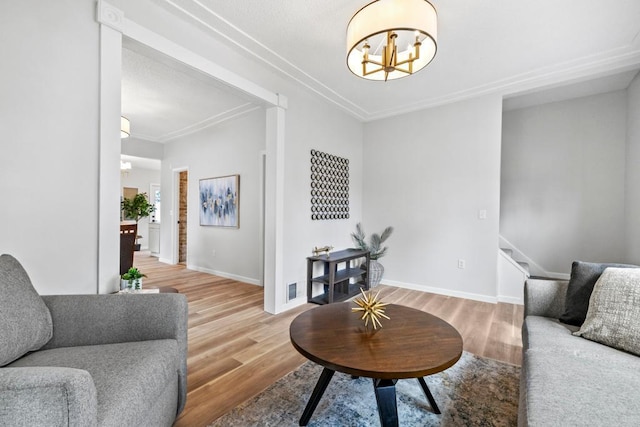 living room with crown molding, stairs, wood finished floors, baseboards, and a notable chandelier