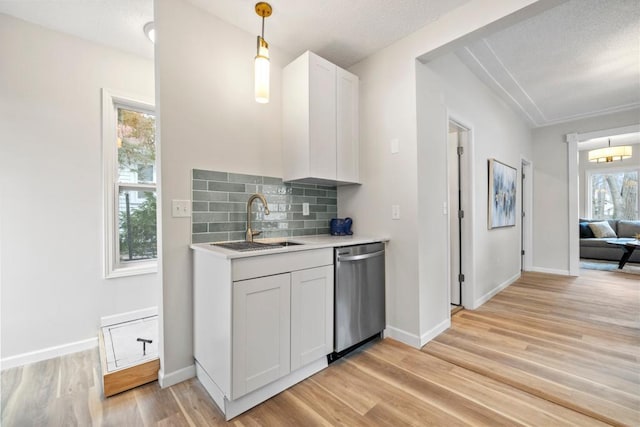 kitchen featuring light countertops, dishwasher, a sink, light wood-style floors, and decorative backsplash