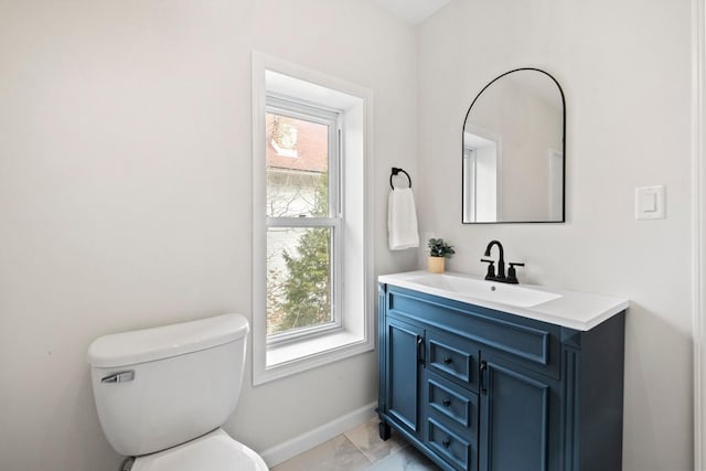 half bathroom featuring vanity, toilet, and baseboards