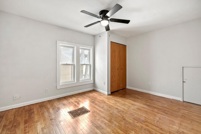 unfurnished bedroom featuring light wood-type flooring, visible vents, a ceiling fan, and baseboards