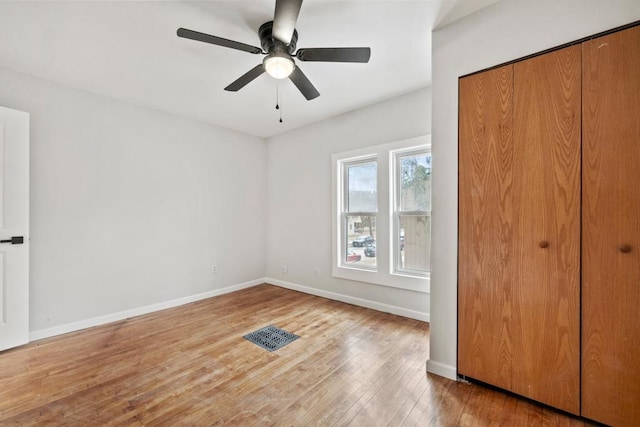unfurnished bedroom featuring wood finished floors, a closet, baseboards, and ceiling fan