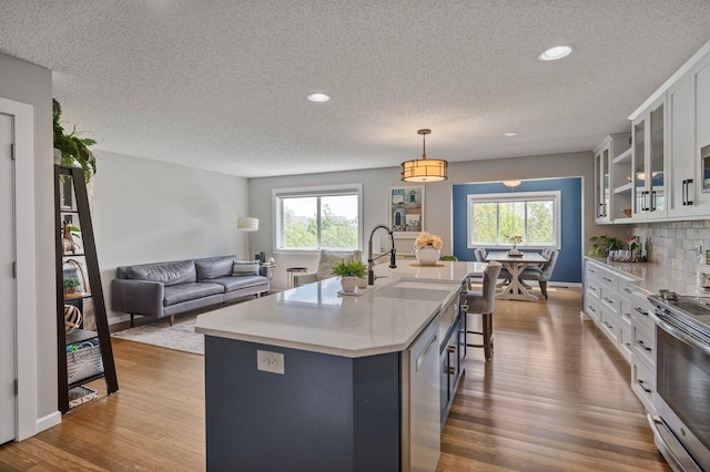 10351 Kittredge Pkwy NE, Otsego, MN 55301 - kitchen featuring stainless steel electric range, a textured ceiling, white cabinets, glass insert cabinets, and healthy amount of natural light