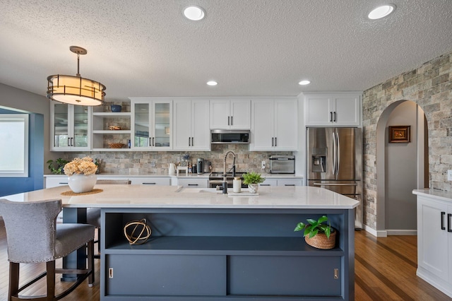 10351 Kittredge Pkwy NE, Otsego, MN 55301 - kitchen featuring stainless steel appliances, arched walkways, a textured ceiling, white cabinetry, and dark wood finished floors