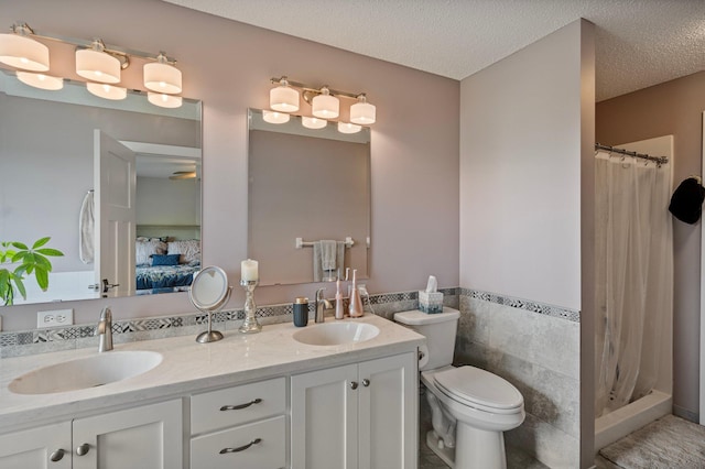 10351 Kittredge Pkwy NE, Otsego, MN 55301 - ensuite bathroom with double vanity, a shower with shower curtain, a textured ceiling, wainscoting, and tile walls