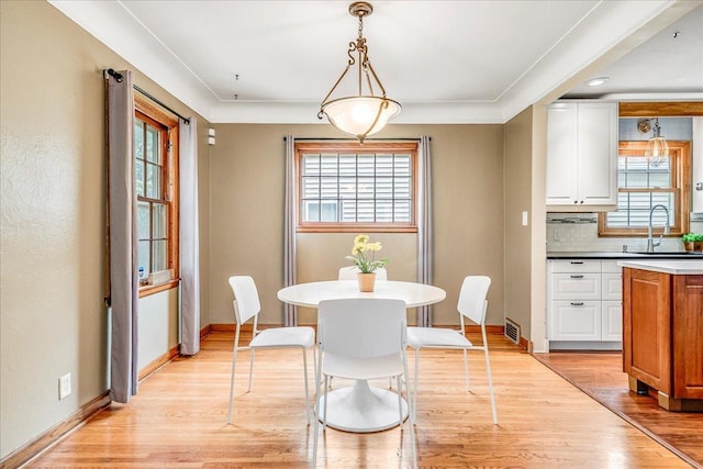 dining room featuring baseboards, a healthy amount of sunlight, and light wood-style flooring
