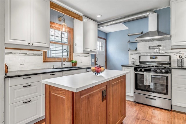 kitchen featuring wall chimney range hood, a center island, a sink, backsplash, and gas stove