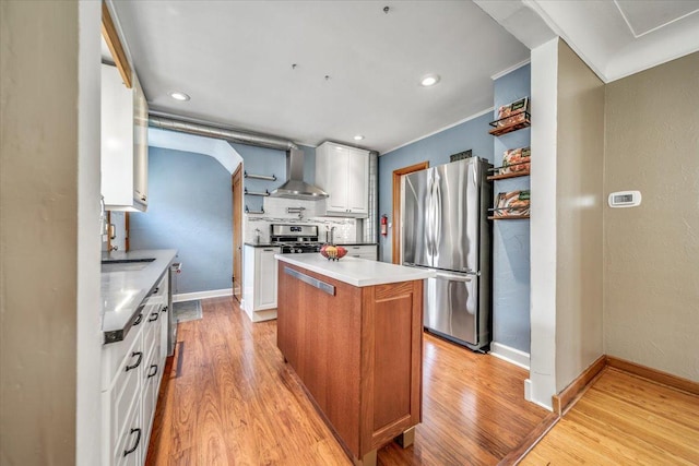 kitchen featuring open shelves, a kitchen island, light wood-style floors, wall chimney exhaust hood, and stainless steel appliances