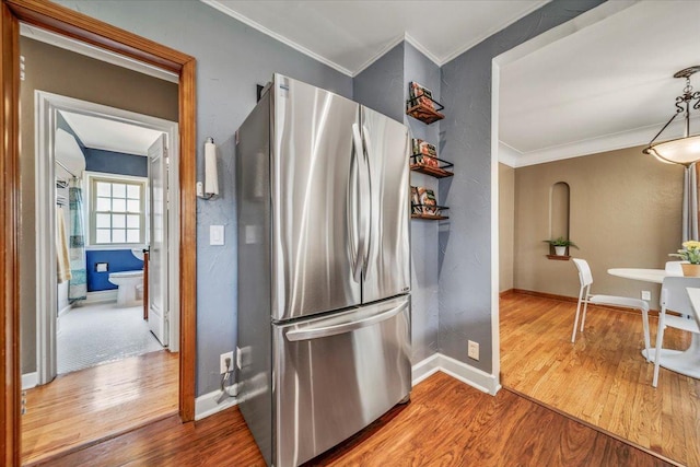 kitchen featuring crown molding, freestanding refrigerator, baseboards, and wood finished floors