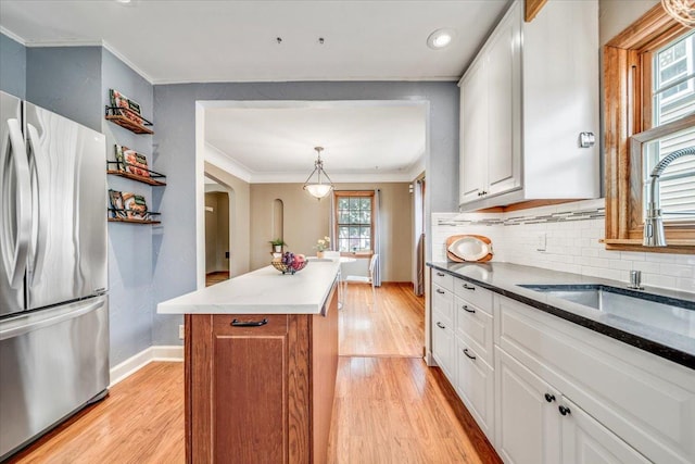 kitchen with baseboards, ornamental molding, freestanding refrigerator, and light wood-style flooring