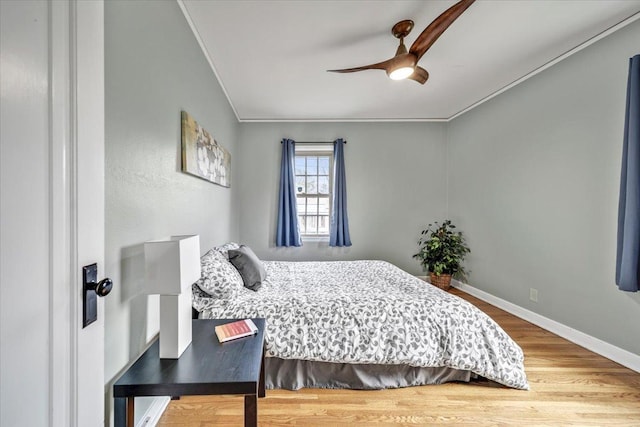 bedroom featuring crown molding, baseboards, ceiling fan, and wood finished floors
