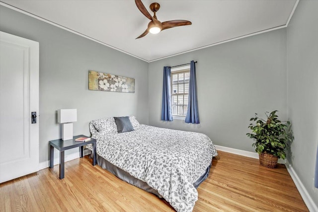 bedroom with crown molding, a ceiling fan, baseboards, and light wood-style flooring