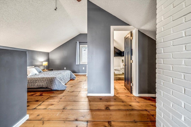 bedroom featuring a textured ceiling, vaulted ceiling, baseboards, and hardwood / wood-style floors