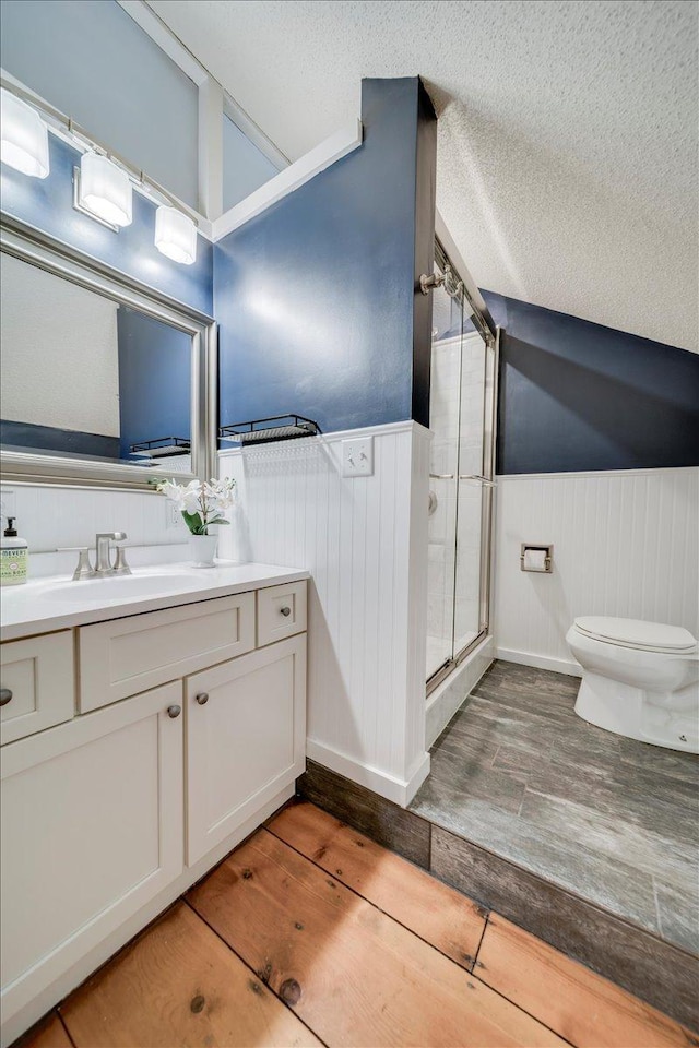 full bath with wood finished floors, a wainscoted wall, toilet, and a shower stall