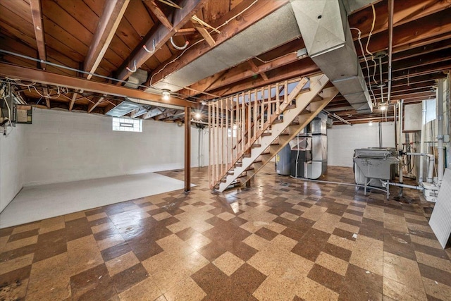 below grade area with water heater, tile patterned floors, heating unit, and stairway