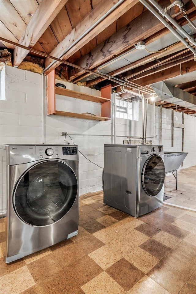 laundry area with laundry area, a sink, washer and clothes dryer, and tile patterned floors
