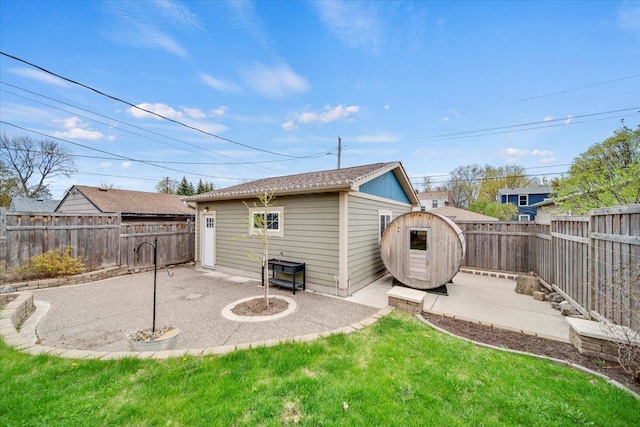 back of property featuring a patio, a fenced backyard, a lawn, and an outbuilding