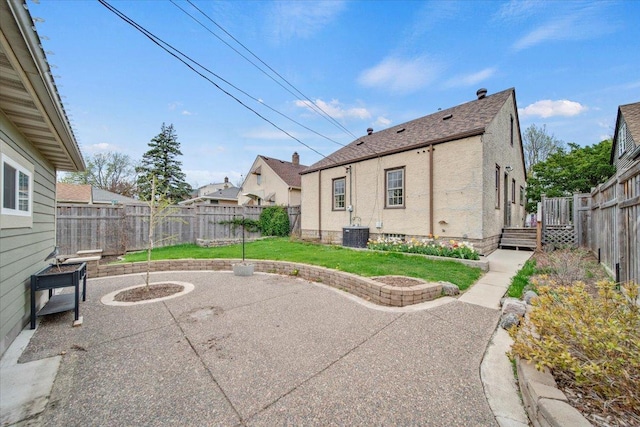 rear view of house featuring central AC, stucco siding, a fenced backyard, a lawn, and a patio