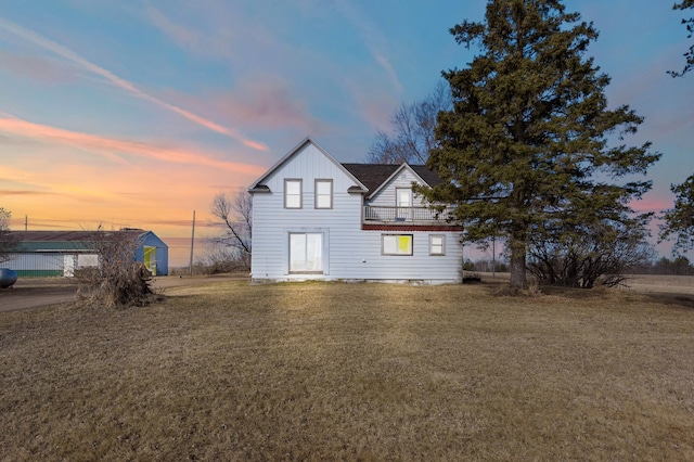 rear view of property featuring a balcony, board and batten siding, and a yard