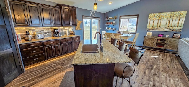 kitchen featuring dark wood-type flooring, a sink, lofted ceiling, and a kitchen breakfast bar
