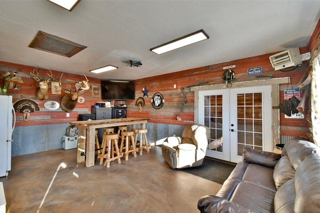 40749 Greencrest Rd, Crow River Twp, MN 56312 - living area with french doors, wooden walls, and finished concrete flooring