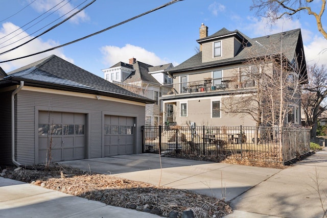 1801 Fremont Ave S Unit 101, Minneapolis, MN 55403 - view of front facade featuring fence, roof with shingles, a chimney, a garage, and concrete driveway