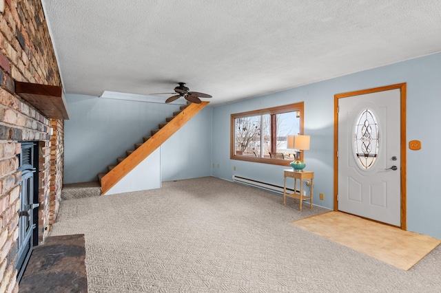 carpeted entrance foyer featuring a baseboard heating unit, a fireplace, stairway, a textured ceiling, and ceiling fan