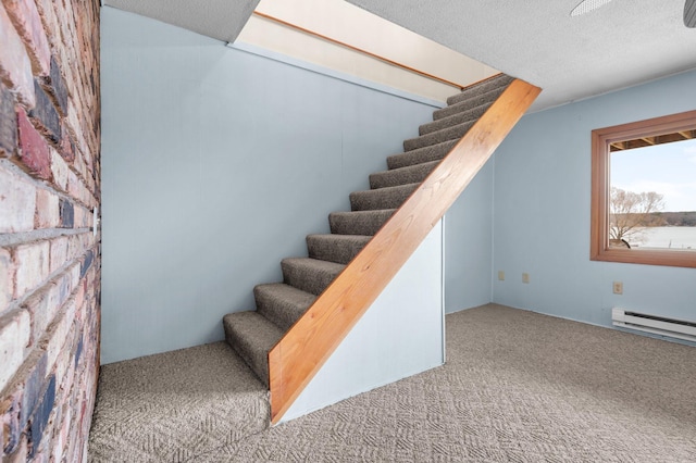 stairway with carpet flooring, a baseboard heating unit, and a textured ceiling