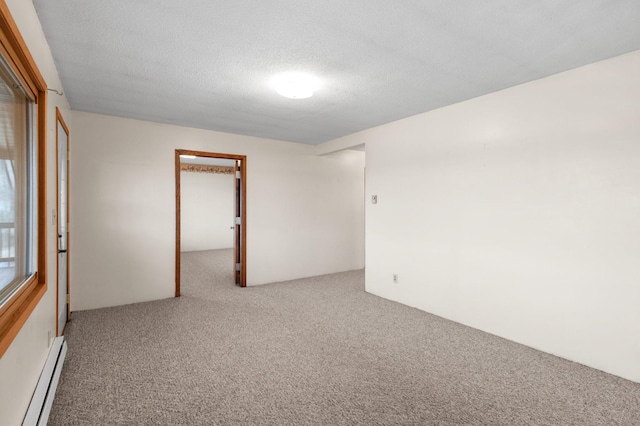 carpeted spare room featuring a baseboard heating unit and a textured ceiling