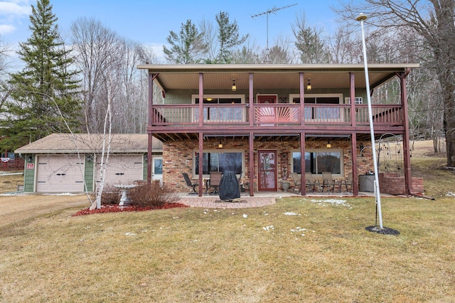 rear view of house with an attached garage, a yard, and a patio area