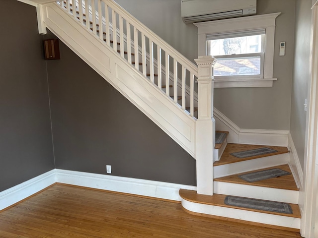 304 7th Pl NW, Austin, MN 55912 - stairway featuring a wall mounted air conditioner, wood finished floors, and baseboards