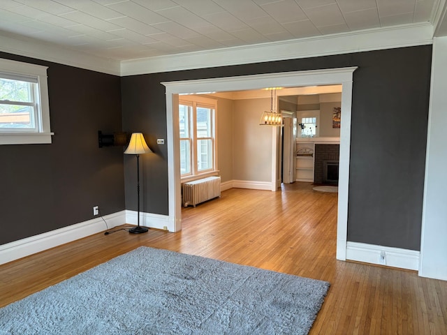 304 7th Pl NW, Austin, MN 55912 - unfurnished room with radiator, crown molding, hardwood / wood-style flooring, baseboards, and a fireplace