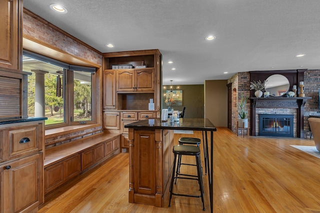 3202 Riviera Rd, Sartell, MN 56377 - kitchen featuring a fireplace, a kitchen bar, a center island, a textured ceiling, and light wood finished floors