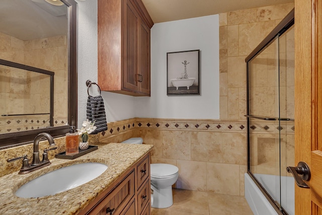 3202 Riviera Rd, Sartell, MN 56377 - bathroom with vanity, toilet, a wainscoted wall, tile walls, and combined bath / shower with glass door