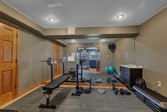 3202 Riviera Rd, Sartell, MN 56377 - workout area featuring visible vents, a textured ceiling, a textured wall, and dark wood-style flooring