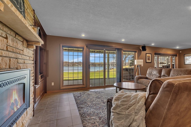 3202 Riviera Rd, Sartell, MN 56377 - living area featuring tile patterned floors, a textured ceiling, a stone fireplace, recessed lighting, and a water view