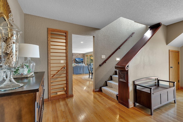3202 Riviera Rd, Sartell, MN 56377 - staircase featuring baseboards, a textured ceiling, a textured wall, and wood finished floors