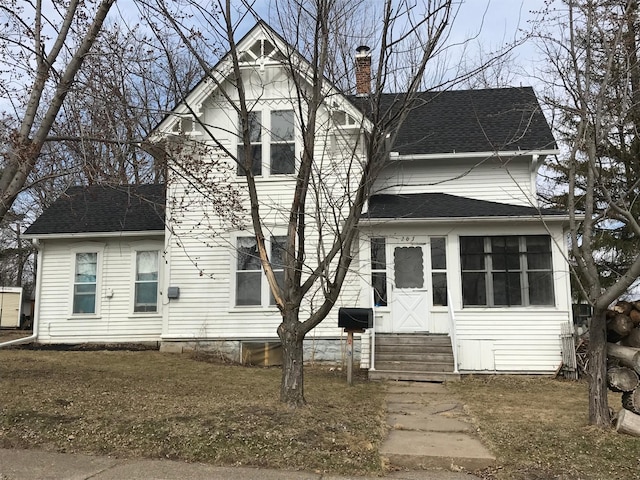 view of front facade with a chimney, entry steps, and roof with shingles