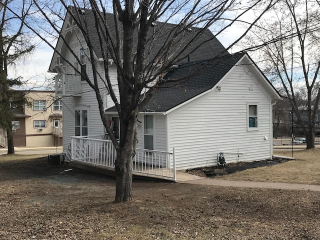 view of property exterior with a shingled roof and a deck