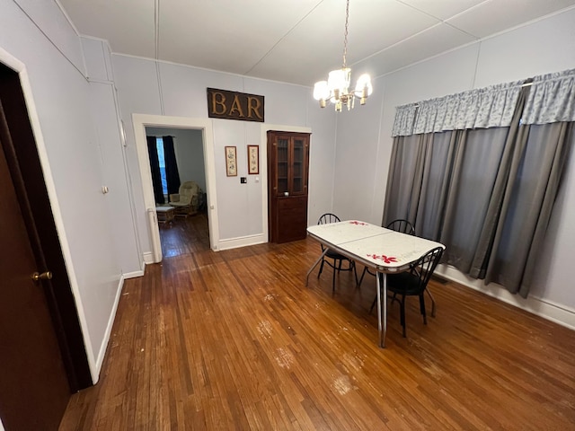 dining area with wood-type flooring, a chandelier, baseboards, and ornamental molding