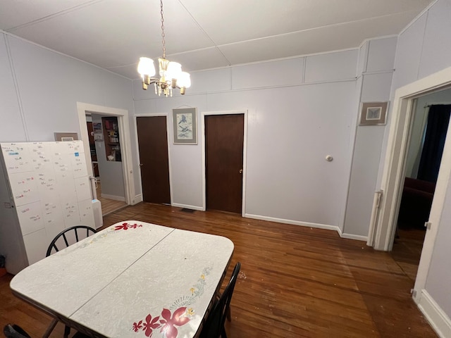 dining room featuring a chandelier, dark wood-type flooring, and baseboards