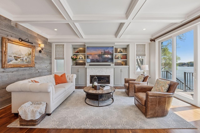 living room featuring wood walls, crown molding, wood finished floors, beamed ceiling, and a fireplace