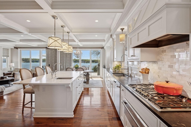 kitchen featuring appliances with stainless steel finishes, premium range hood, a breakfast bar area, and a sink