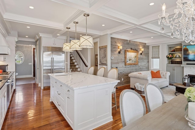 kitchen featuring a sink, coffered ceiling, a kitchen breakfast bar, open floor plan, and white cabinets