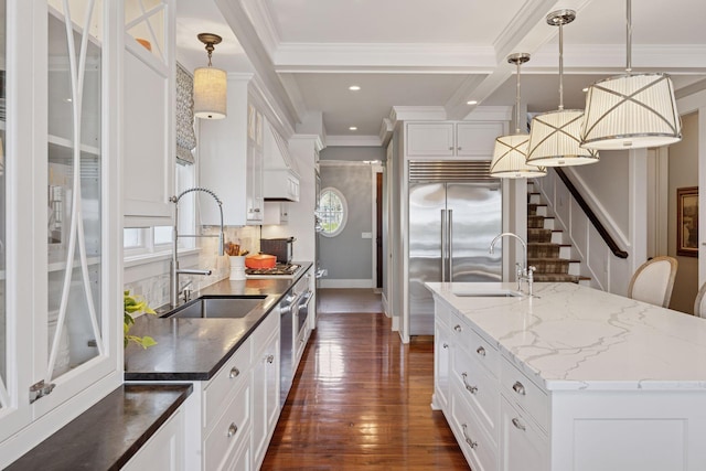 kitchen with a sink, ornamental molding, dark wood finished floors, and a center island with sink